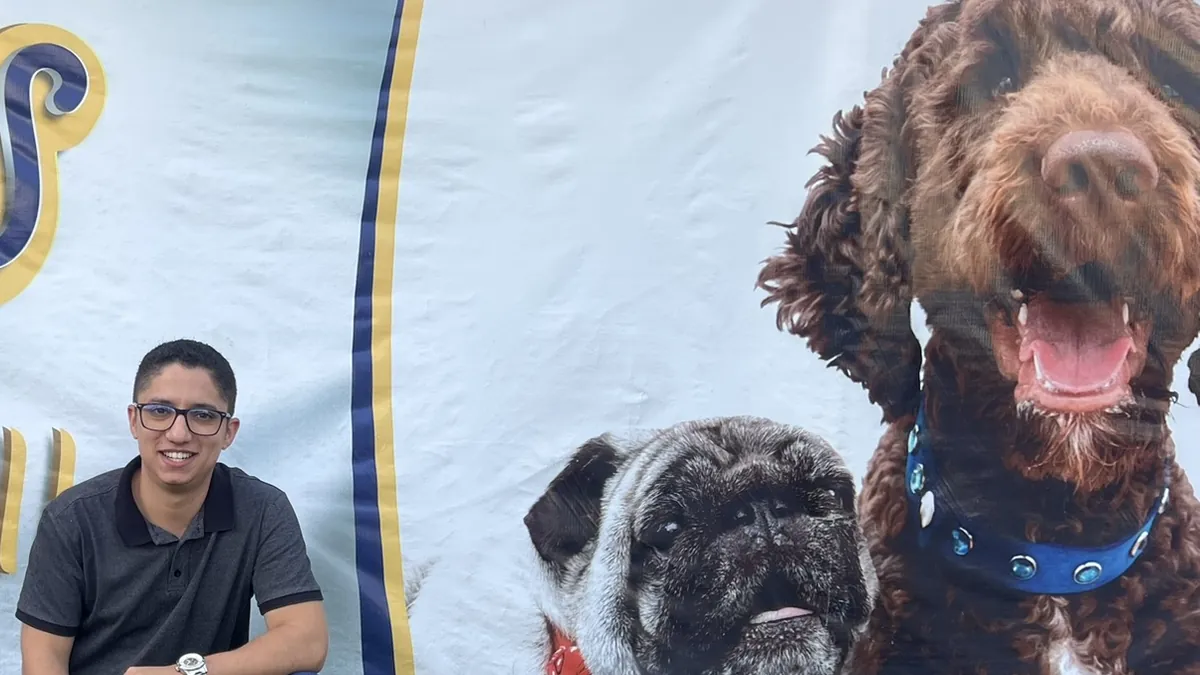 Thiago Carvalho, da Agência 4 Patas, em frente ao banner de um cliente do nicho pet
