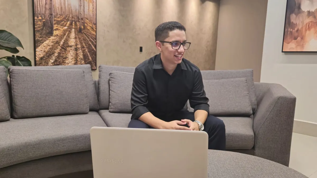 Thiago Carvalho, da Agência 4 Patas, sentado no sofá diante do notebook